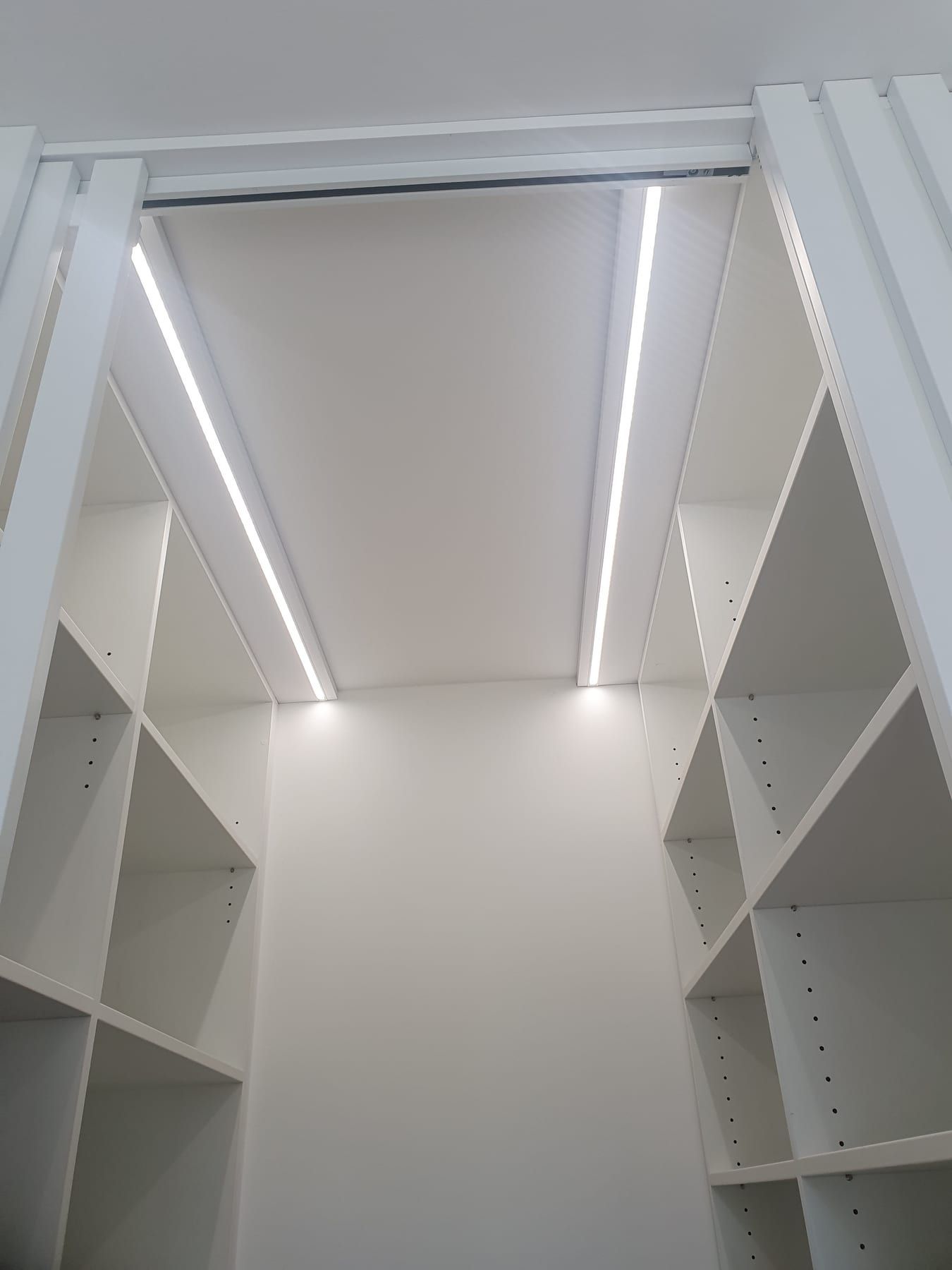 Šatna s policemi po obou stranách a LED pásem vedeným v podhledu